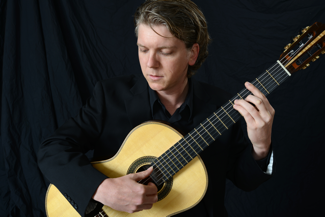 Photo of Adam Kossler playing a guitar